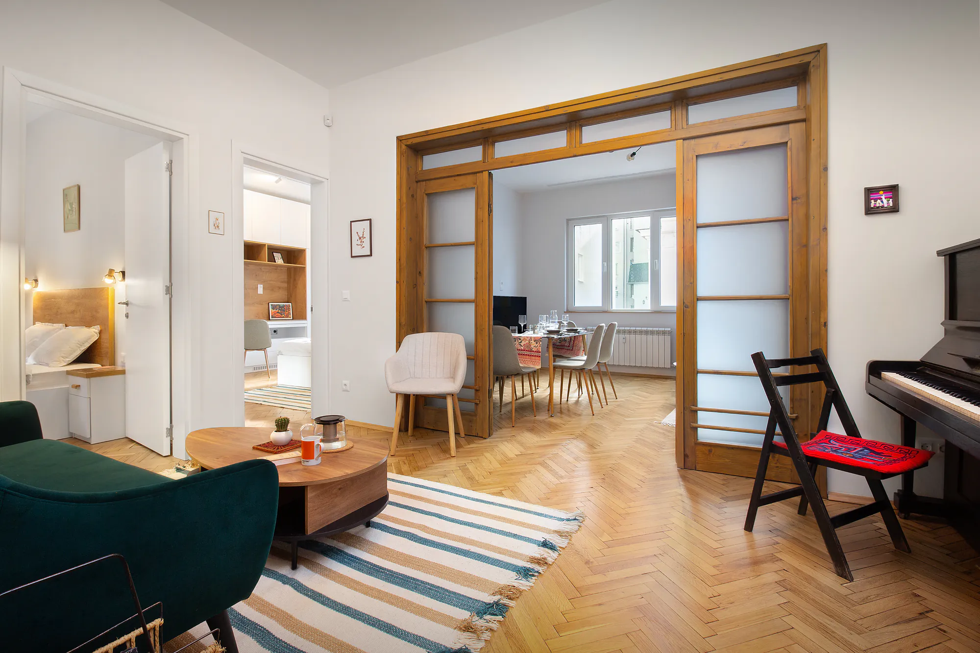 Living room with restored wooden sliding doors to the dining room, a piano and herringbone parquet
