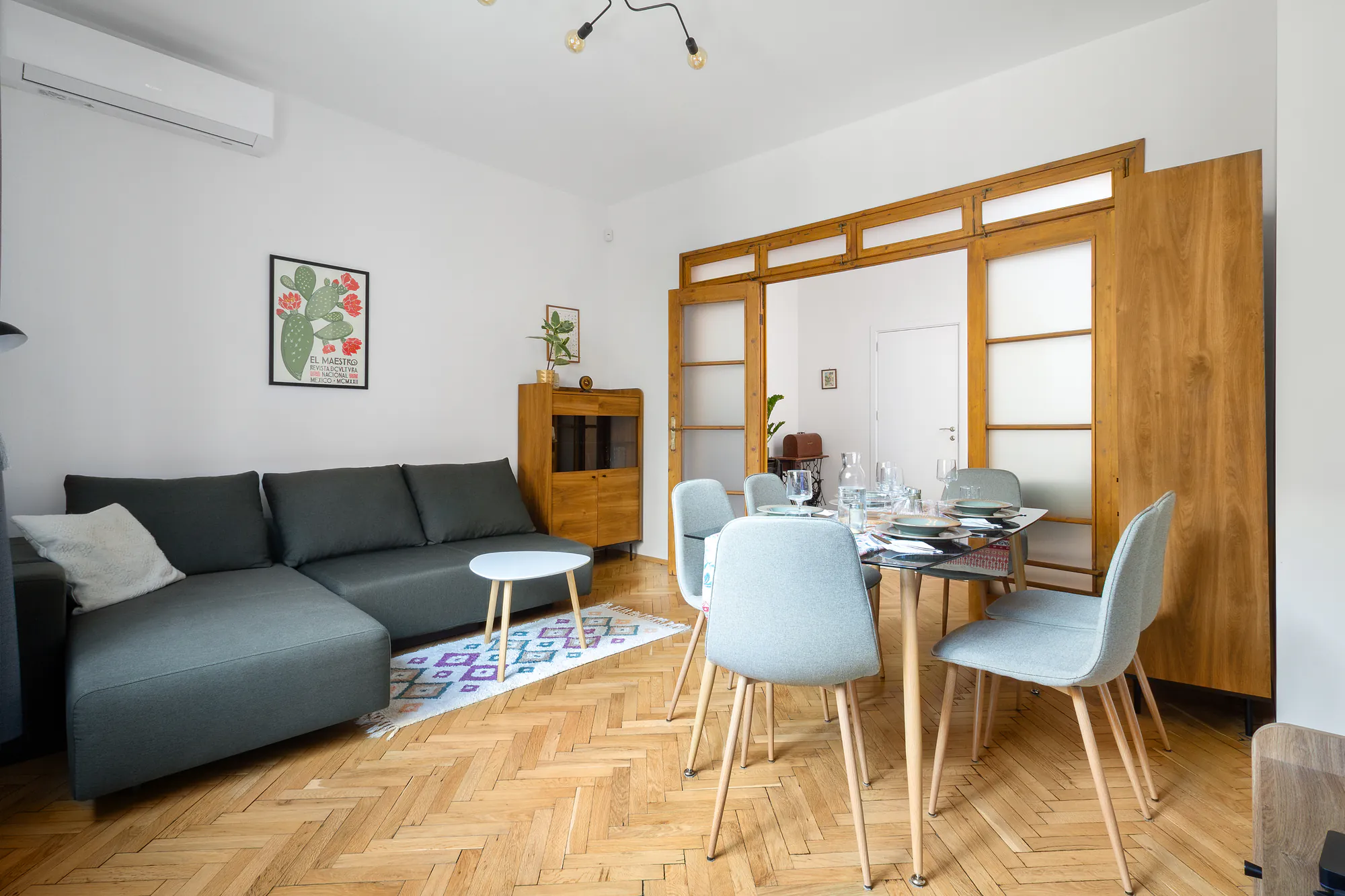 Living room with dining area, grey corner sofa, wooden sideboard and herringbone parquet