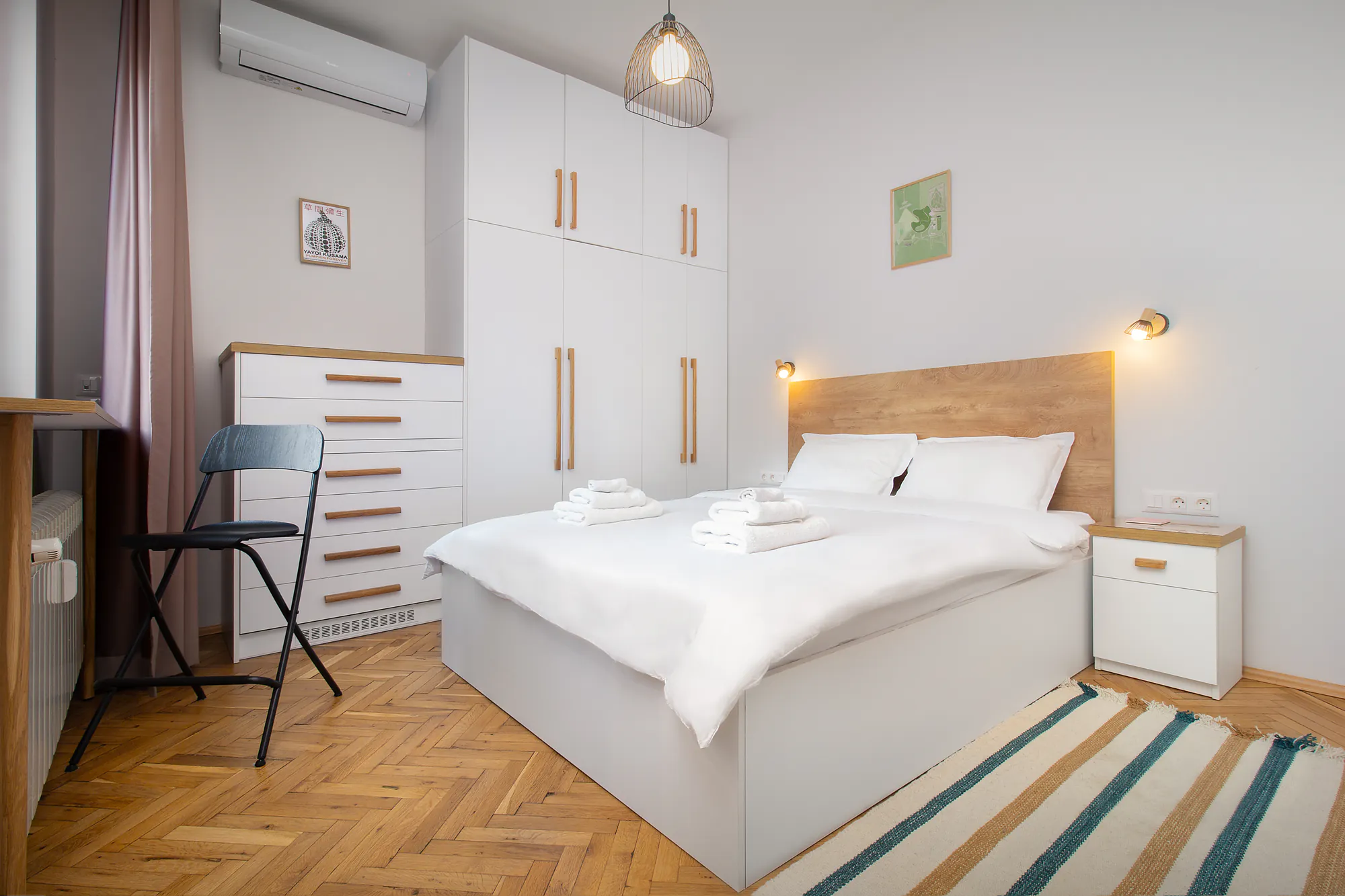 Bedroom with a white wardrobe, wooden headboard and herringbone parquet