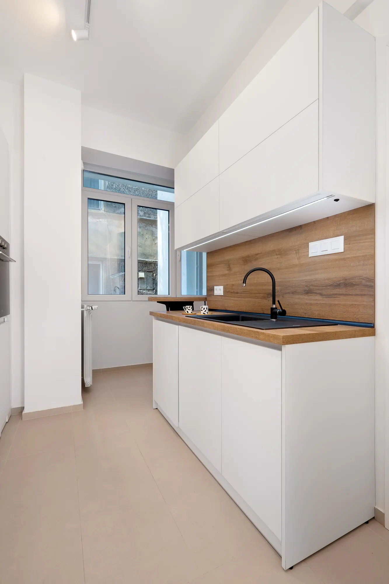 Kitchen with white cabinets, wooden worktop, black sink and black tap