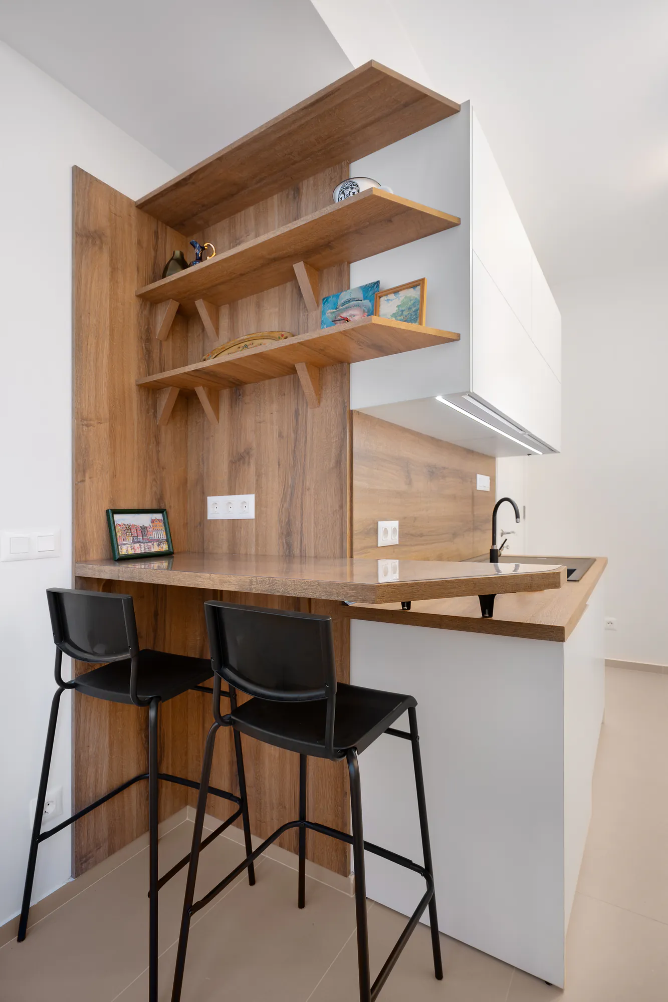 Kitchen bar counter with open wooden shelves and black bar stools