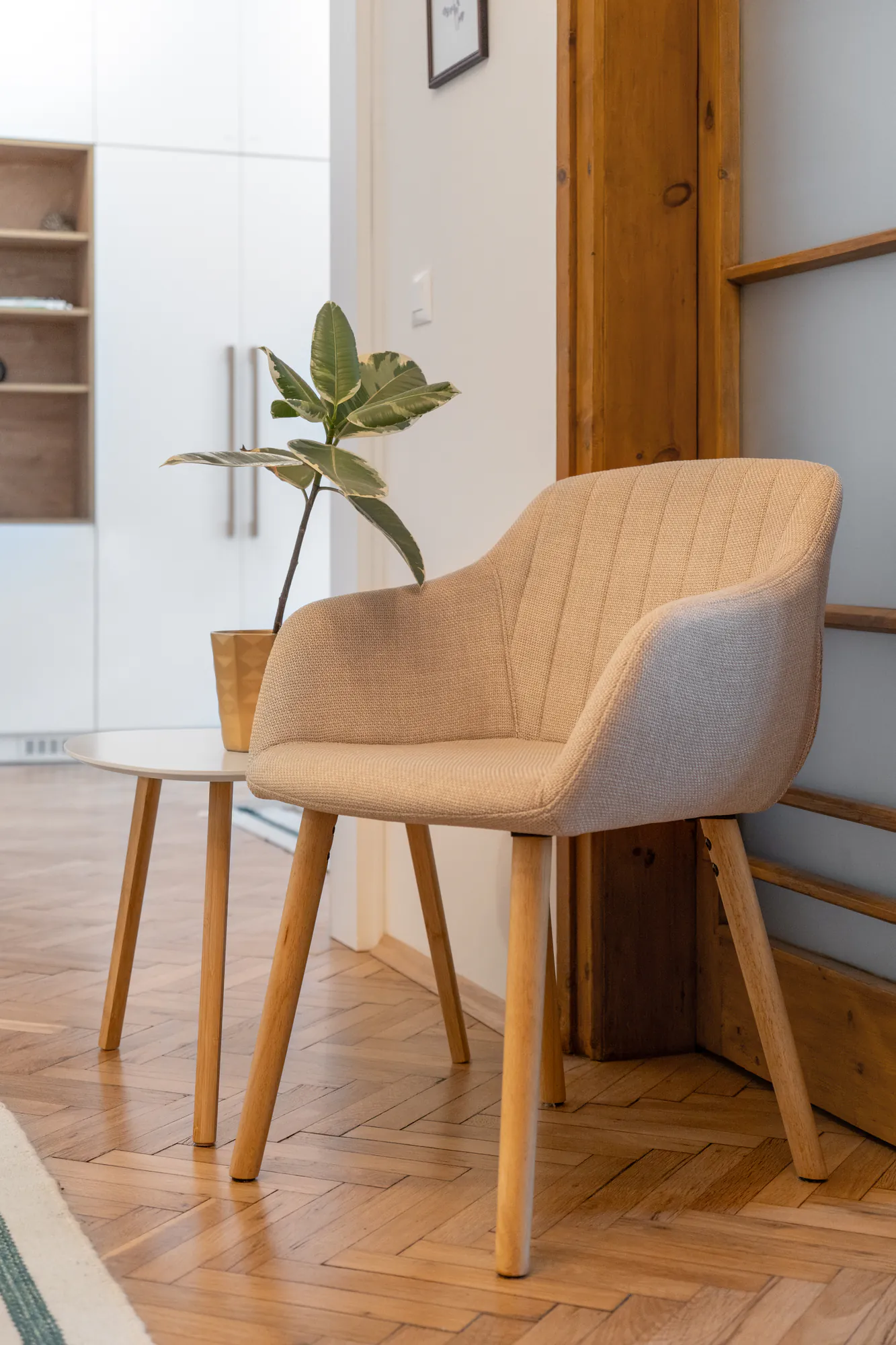 Living room detail: upholstered armchair and a plant next to a restored wooden door