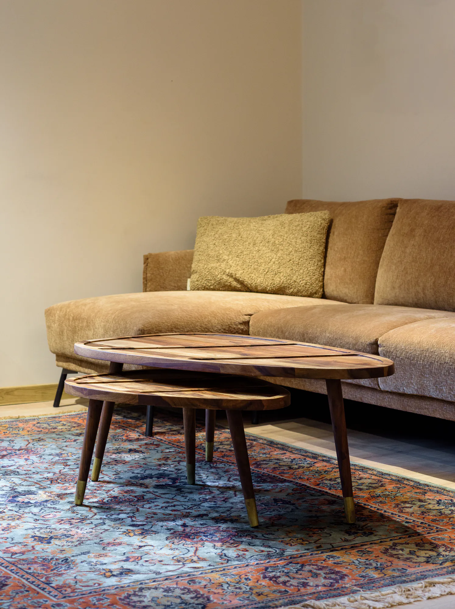 Living room detail: wooden coffee tables with brass feet on a patterned rug