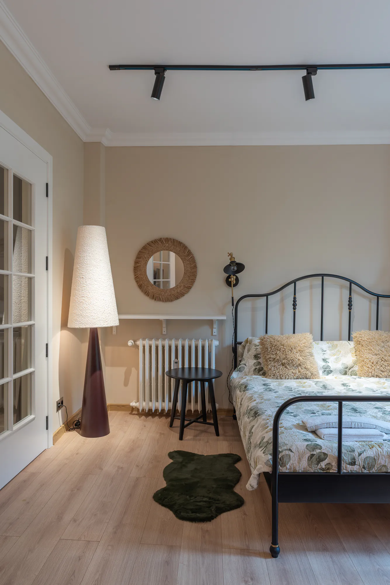 Bedroom with a metal bed, floor lamp and a glazed door
