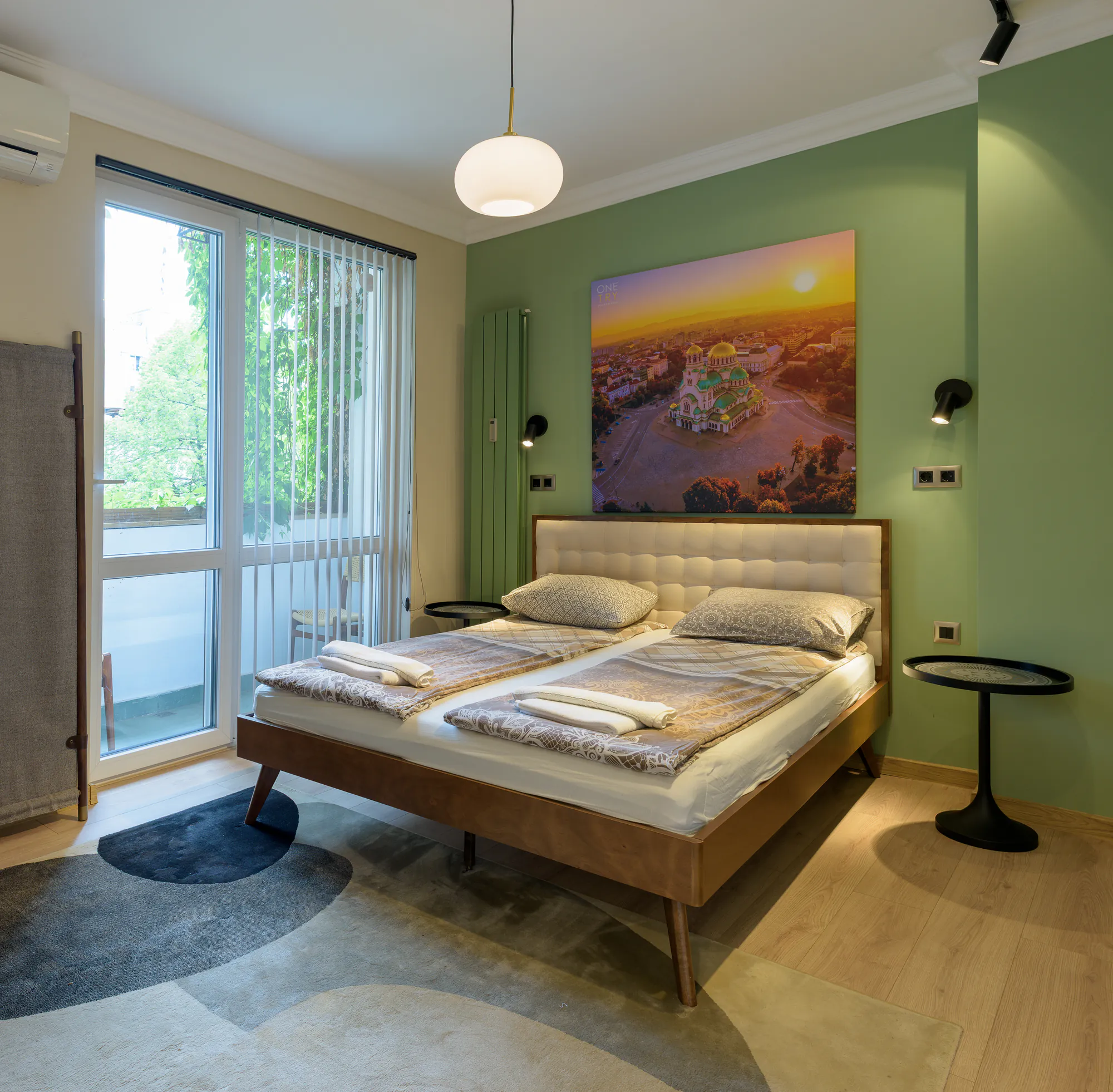 Second bedroom with green walls, an upholstered headboard and a balcony door