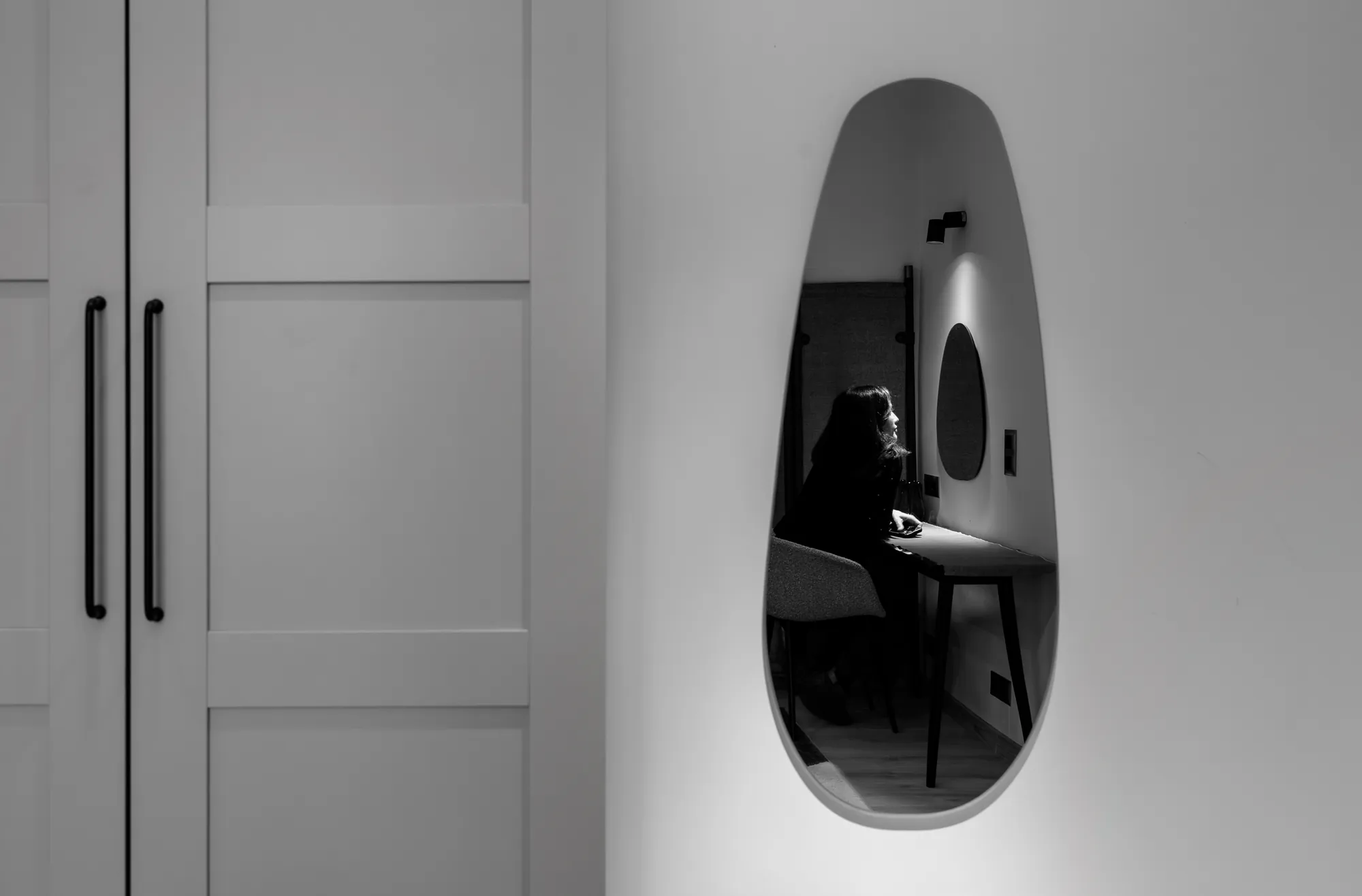Organic-shaped mirror next to the wardrobe, black and white photo