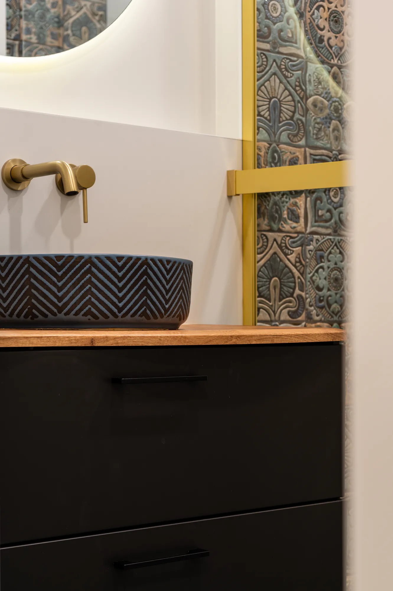 Detail: brass tap, dark blue basin and a wooden top