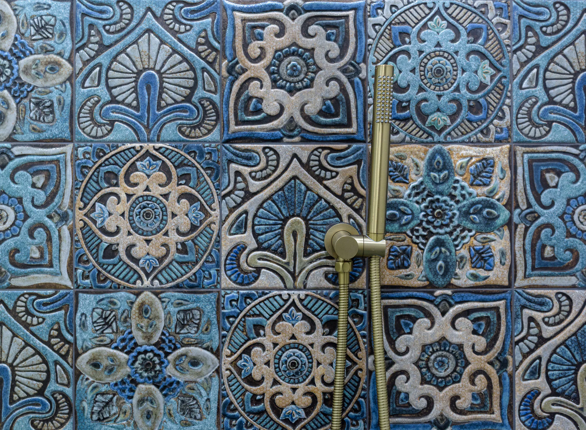 Handmade blue tiles with a brass hand shower