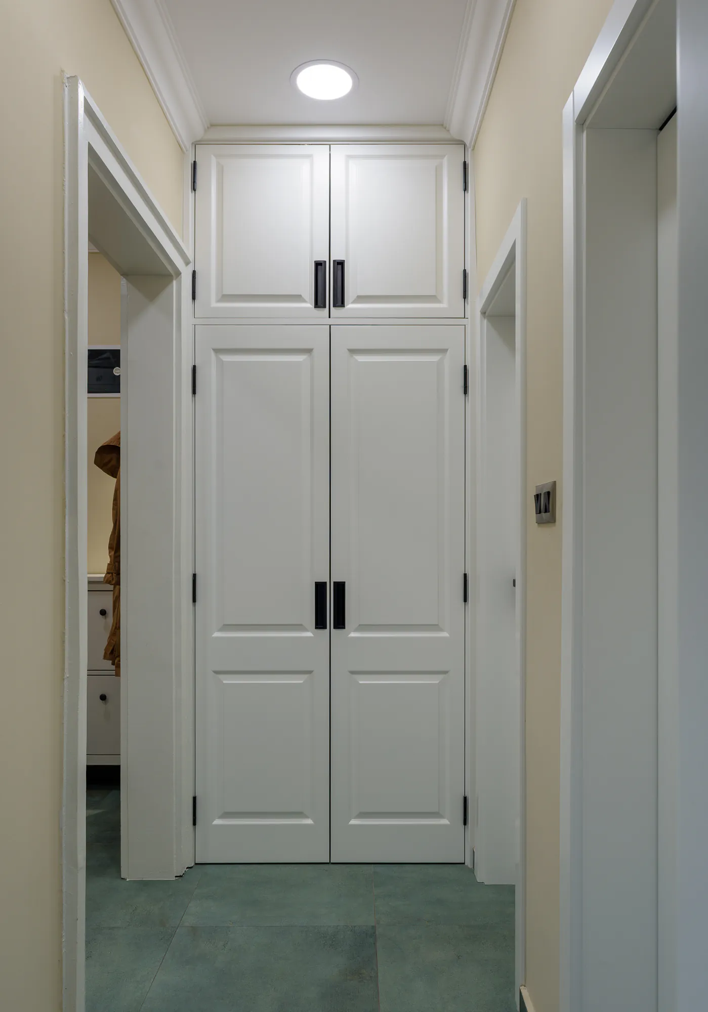 Corridor with a built-in white wardrobe and green floor tiles