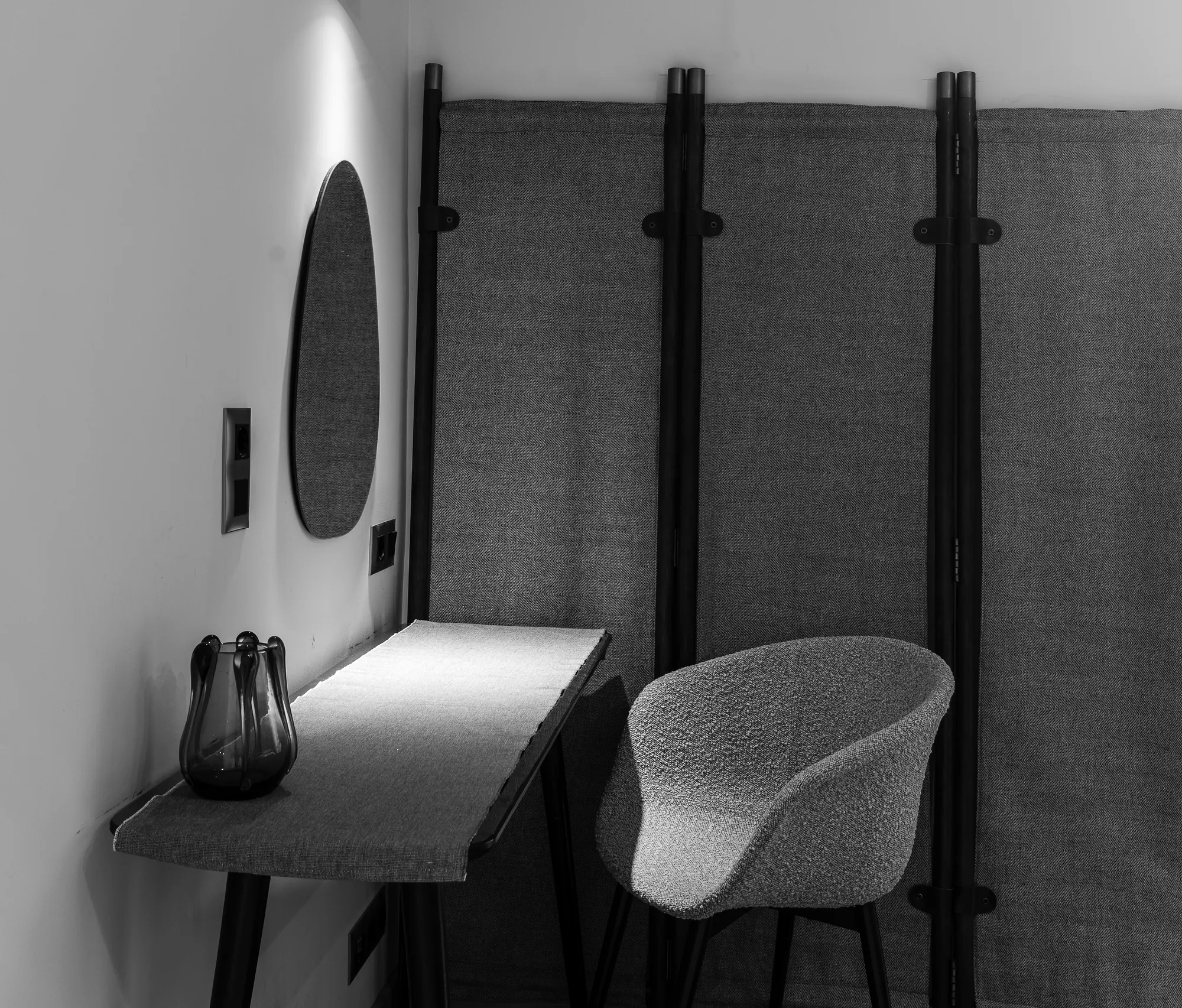 Corner with a console, mirror, screens and an upholstered chair, black and white photo